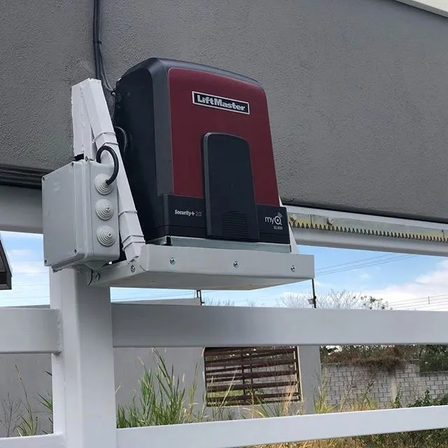 Motor LiftMaster montado sobre el riel de un portón corredizo.