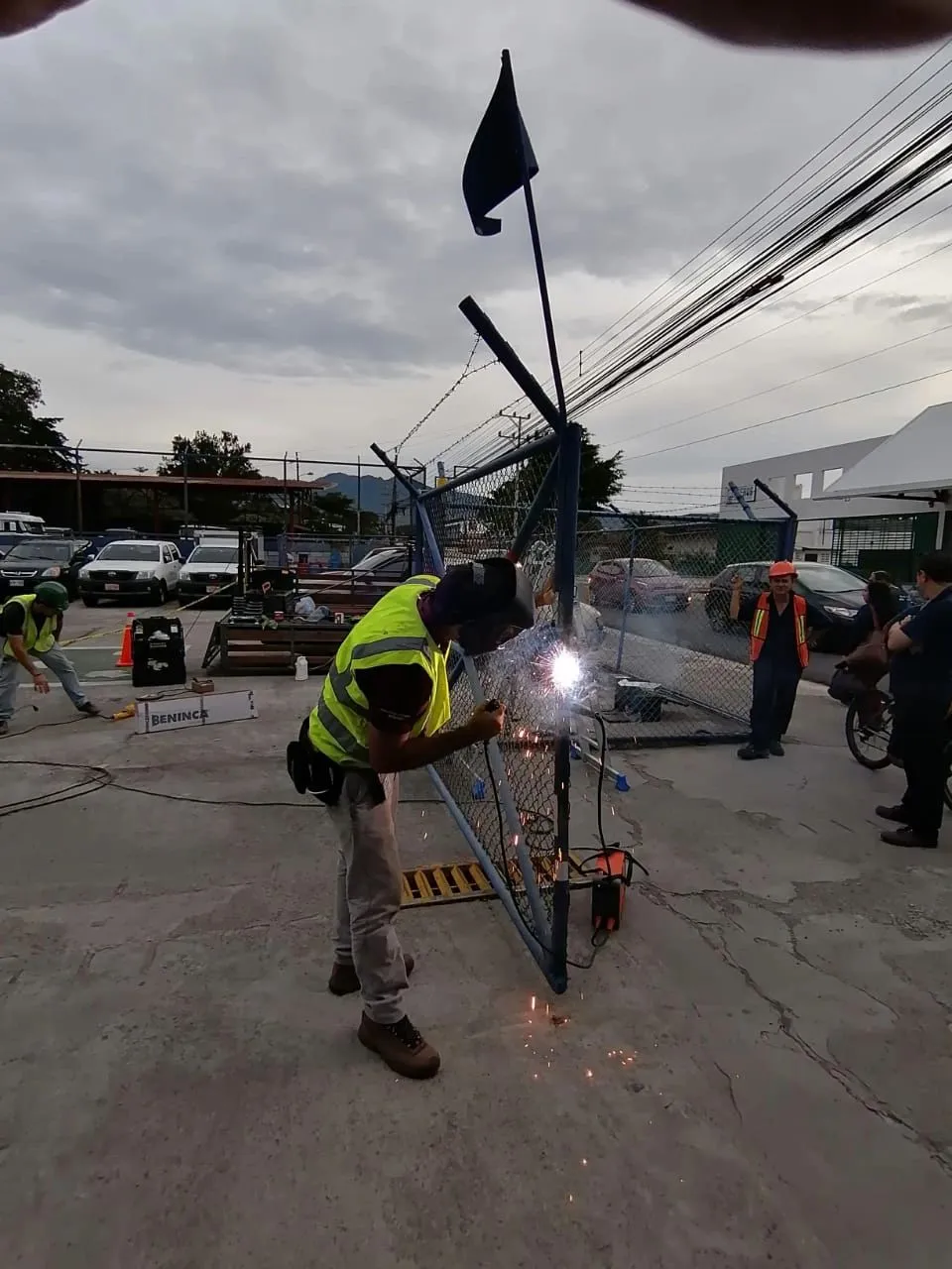 Técnico soldando la estructura de un portón en un parqueo.